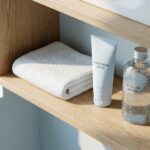 Produk BREVA: Sunscreen SPF 50 dan Micellar Water di rak kayu minimalis. Perawatan kulit premium untuk wajah cerah terlindungi.